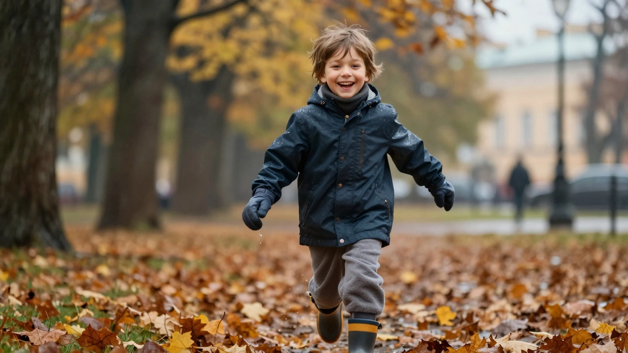 Ребёнок бежит по парку в дождливую осень в водонепроницаемой куртке, перчатках и ботинках, смеётся, листья вокруг.