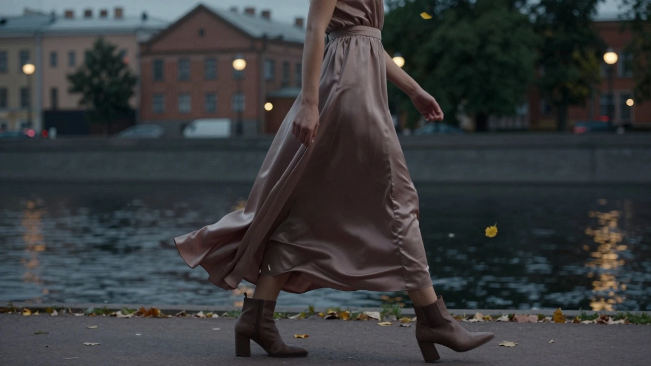 Длинное платье с разрезом на щиколотке и ботильонами на блоке, идущее по берегу Невы осенью.