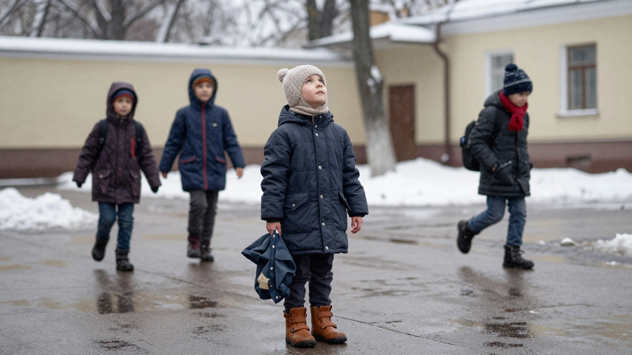 Ребёнок 5–6 лет стоит на мокрой улице, держит дождевик, вокруг — другие дети, уходящие в школу.