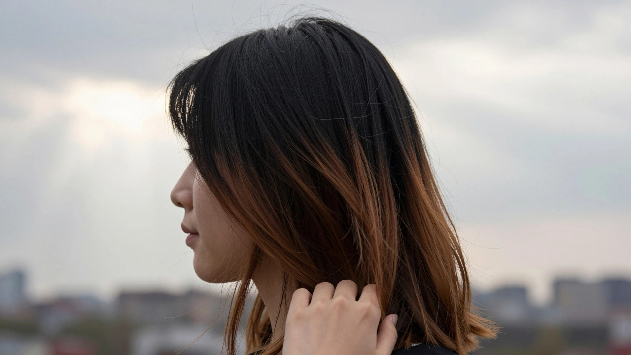 Профиль женщины с переходом от черного к карамельному оттенку волос, мягкий солнечный свет выделяет светлые пряди.